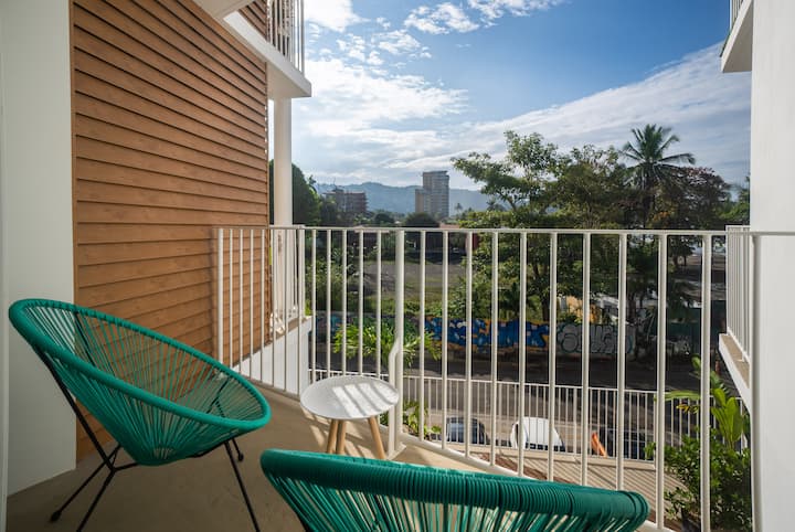 Balcony with teal Acapulco chairs and mountain town view