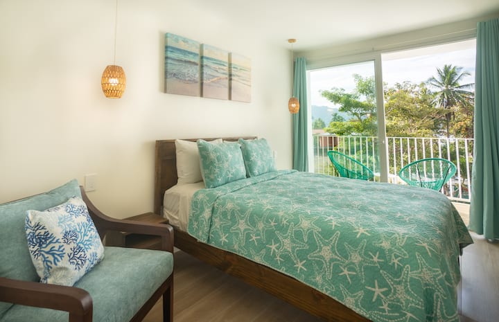 Bedroom with palm tree art and natural light from balcony