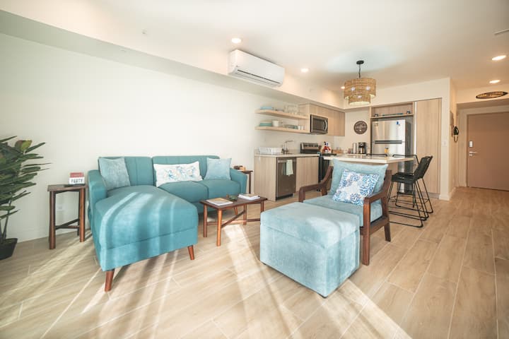 Casa Tica living room with teal sofa, natural light, and open kitchen