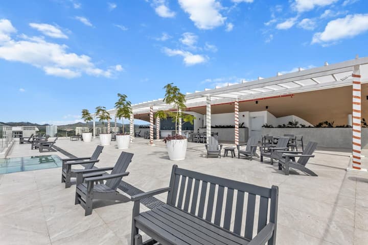 Rooftop deck with Adirondack chairs, pool, and palm trees